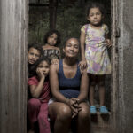 Yubisay Elena Sanchez Garcia, 42, surrounded by 4 of her 10 children. .She is living with two other families in what amounts to be a shack on a river bank in the border town of Cúcuta, Colombia. Because they don’t have proper documentation from the Venezuelan government, something that would be near impossible to obtain, her kids cannot attend school in Colombia. Like other migrants she can only work under the table without proper documentation, leading to a precarious existent for her and her family.  “I know the living conditions here look bad, but it’s better than what we faced in Venezuela. I go out at night to collect rubbish to recycle. I do it while the children are asleep because I can’t do anything during the day. After all they aren’t allowed to go to school here so I work at night. It’s not easy paying rent and feeding them, collecting trash doesn’t pay much. All I really want for them is to go to school.